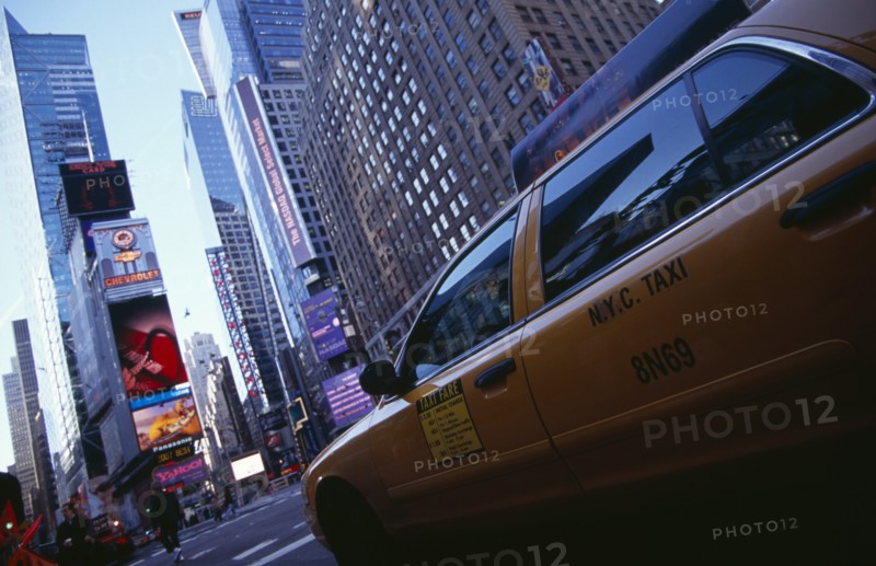 USA, New York, New York City, Times Square.  Yellow taxi cab on street with skyscraper buildings and illuminated advertising.