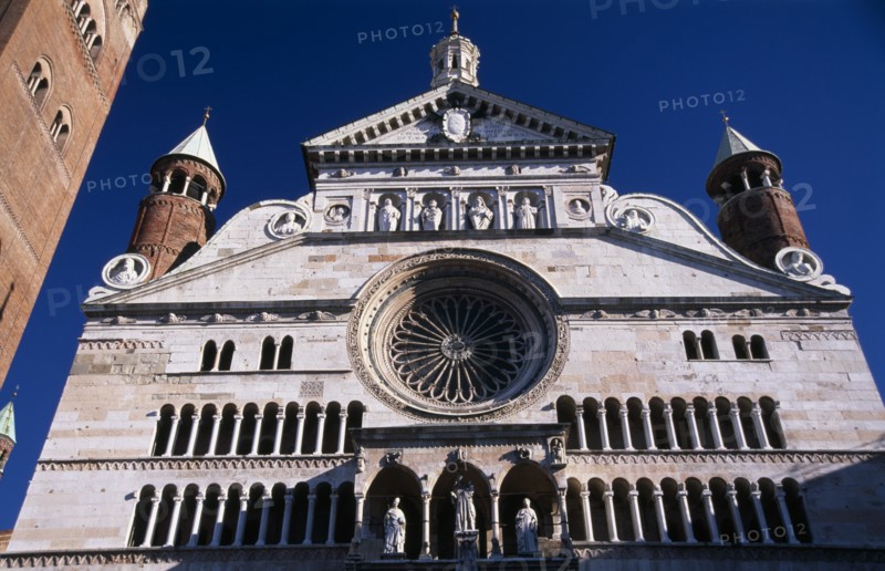 ITALY, Lombardy, Cremona, Piazza del Comune.  Part view of exterior facade of the Duomo with thirteenth century rose window and portico with statues of the Virgin and saints.