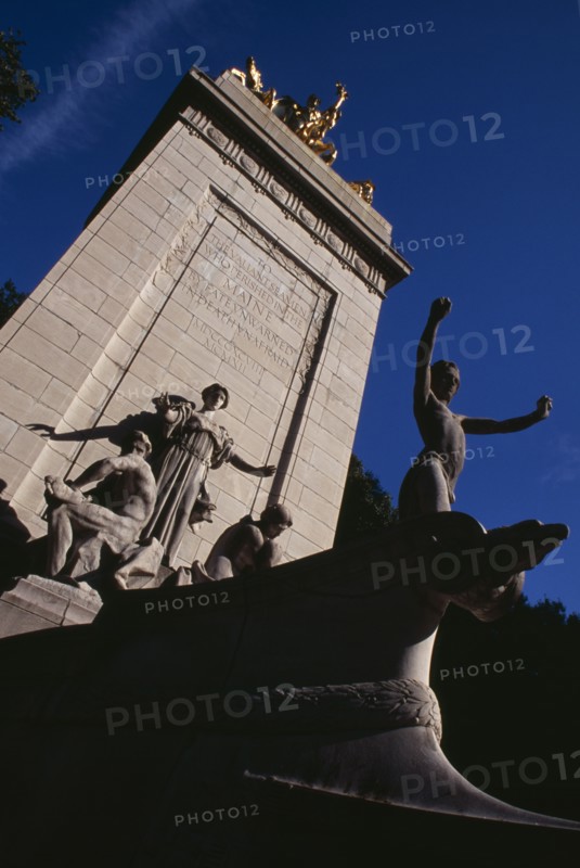 USA, New York, New York City, The Maine Monument  at the Merchants Gate entrance to Central Park.  Limestone pylon crowned with gilded bronze statue of Columbia triumphant.   Dedicated to the 260 seamen who died on the battleship Maine in 1898.  Beaux-arts sculpture by Attilio Piccirilli.