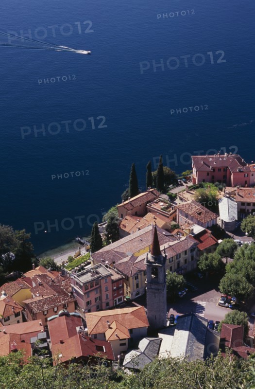 ITALY, Lombardy, Lake Como, "Varenna.  Looking down on red tiled rooftops, church and bell tower of town overlooking lake and distant speed boat."