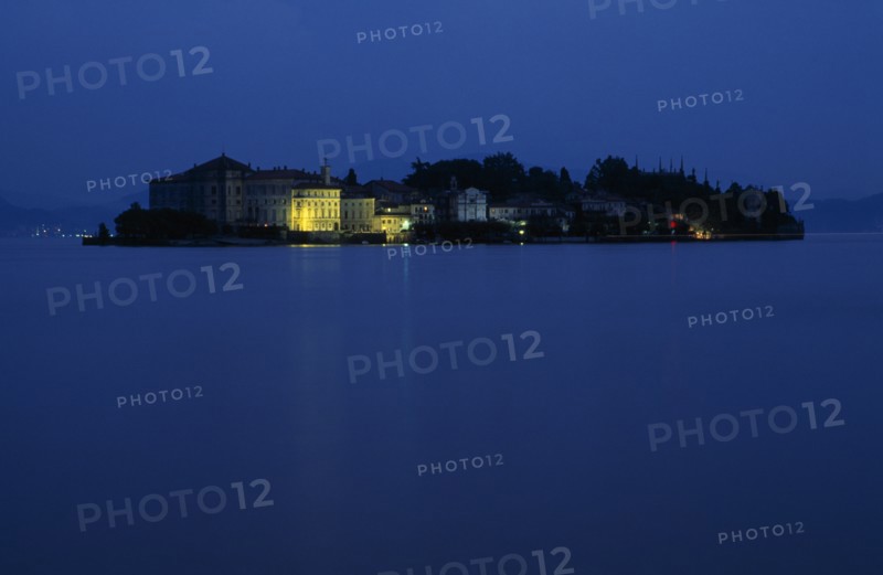 ITALY, Piedmont, Lake Maggiore, Borromeo Islands.  View across lake towards small rocky island of Isola Bella with Palazzo Borromeo illuminated at night.