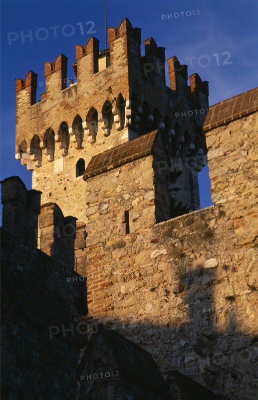 ITALY, Lombardy, Lake Garda , "Sirmione.  Rocca Scaligera medieval castle, detail of fortified tower and crenellated walls with visitor looking out from tower top."