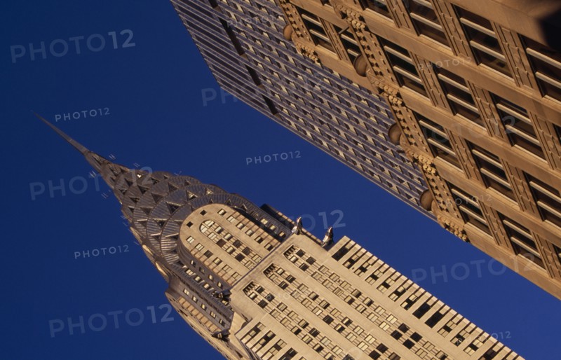 USA, New York, New York City, Angled view of the Chrysler Building from Lexington Avenue beside ornamented tower block exterior.  Steel framed Art Deco skyscraper built 1928-1930. Designed by architect William Van Alen.