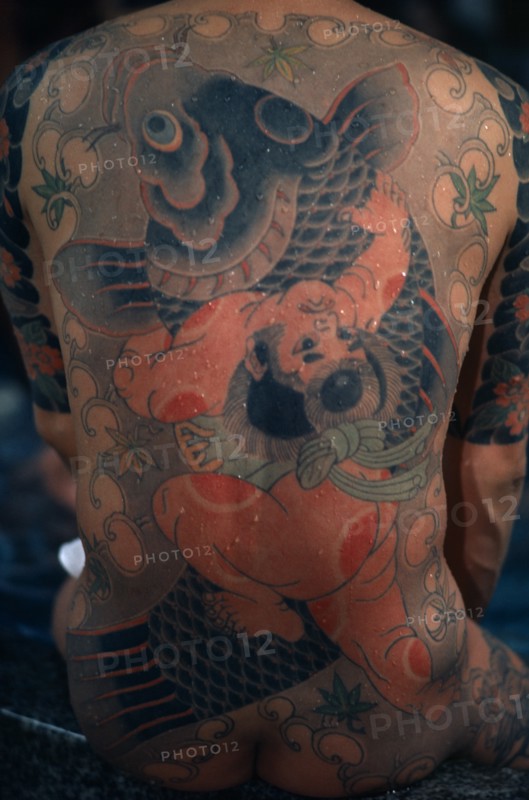 JAPAN, People, Yakuza, "Heavily tattooed back of gangster or Yakuza gang member in public bath house.  Design depicts a carp, a symbol of vigour and energy, ‘ikioi’, from its ability to swim against the current and leap waterfalls."