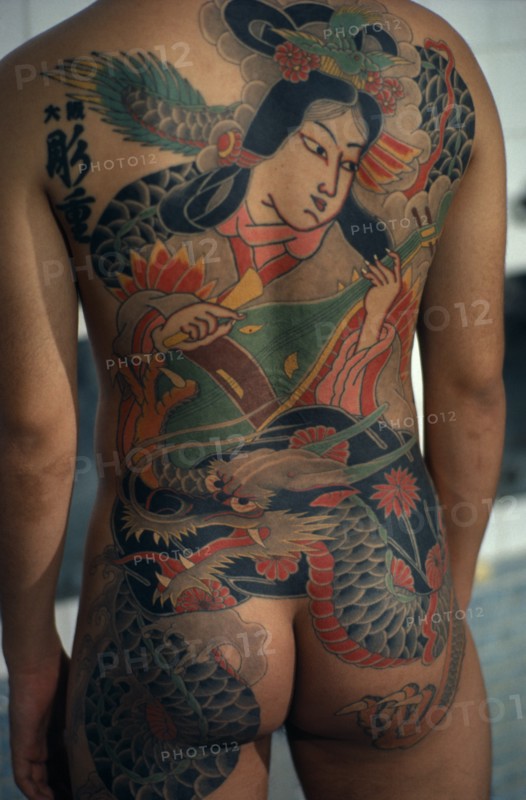 JAPAN, People, Yakuza, Cropped shot of heavily tattooed back of gangster or Yakuza gang member in public bath house.  Design depicts a musician and dragon.
