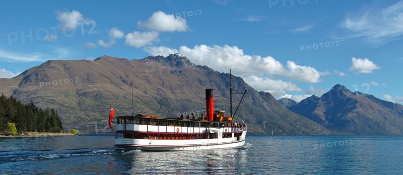 NEW ZEALAND, SOUTH ISLAND, OTAGO, "QUEENSTOWN, VINTAGE STEAMSHIP TSS EARNSALW LEAVING STEAMER WHARF AT QUEENSTOWN TAKING TOURISTS AND SAILING ON LAKE WAKATIPU WITH CECIL PEAK AND WALTER PEAK (FAR R) BEHIND."