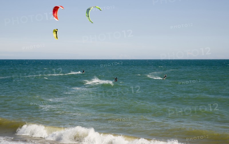 ENGLAND, West Sussex, Lancing, Kite Surfers on sea next to beach in the summer with blue sky