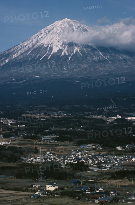 JAPAN, Honshu, Mount Fuji, Snow capped peak of Mount Fuji rising up behind houses and agricultural land.