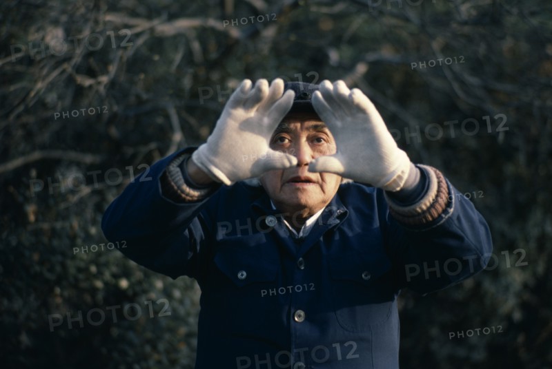 CHINA, Shanghai, "Man doing early morning T’ai Chi Chuan, the ancient Chinese discipline of physical training in a small riverside park.  Face partly framed by outstretched hands."