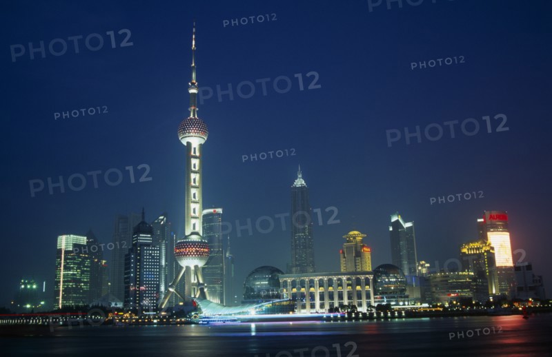 CHINA, Shanghai, Pudong at night with illuminated skyscrapers and buildings including the Oriental Pearl Tower and Jin Mao Building.