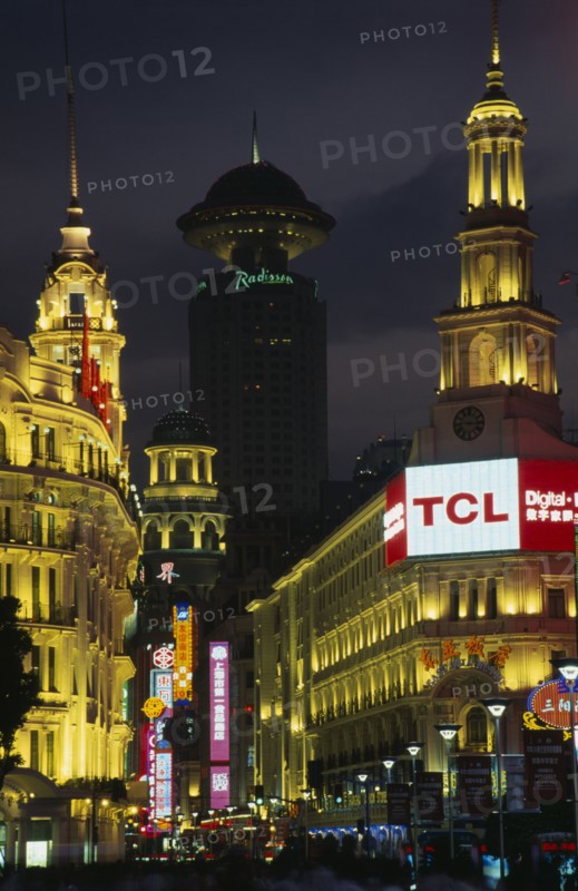 CHINA, Shanghai, "Nanjing Lu.  Looking towards Renmin Square or the People’s Square at night with illuminated buildings and neon signs.  Crowds in foreground, radio tower behind. "