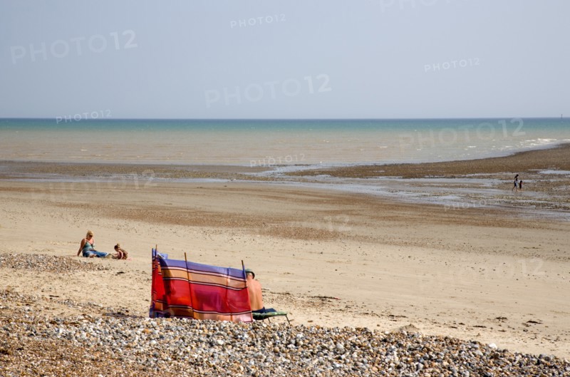 ENGLAND, West Sussex, Littlehampton, View towards the sea from beach with sunbathers behind colourful wind break on sand