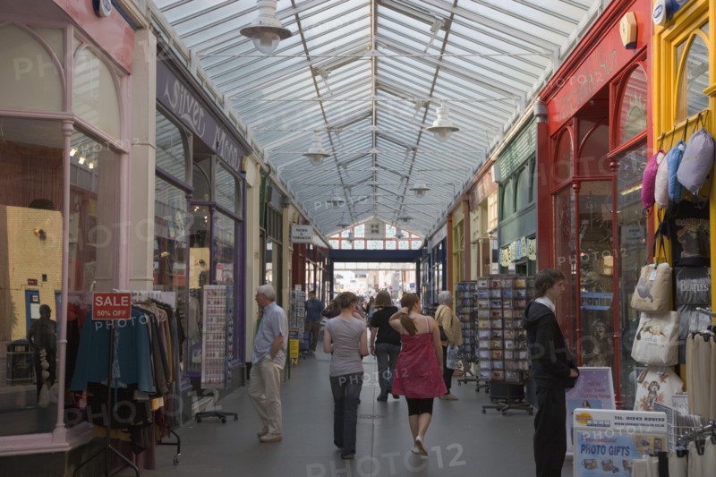 ENGLAND, West Sussex, Bognor Regis, Interior of The Bognor Arcade with people walking through in-between colourful shop fronts