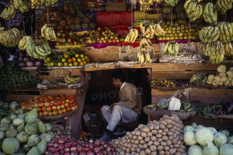 INDIA, Himachal Pradesh, Manali, Vendor amongst fruit stall