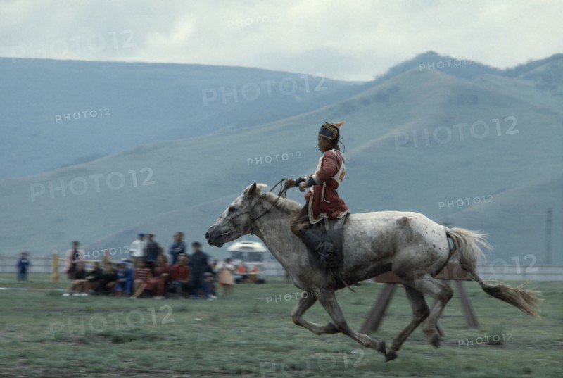 MONGOLIA, Ulan Bator, "Nadam  National Day  Child jockey coming to end of 20 mile cross country horse race, all jockeys must be under 12 years old    child will weigh less and not overstretch the horse. Ulaan Baatar East Asia Asian Baator Children Equestrian Mongol Uls Mongolian "