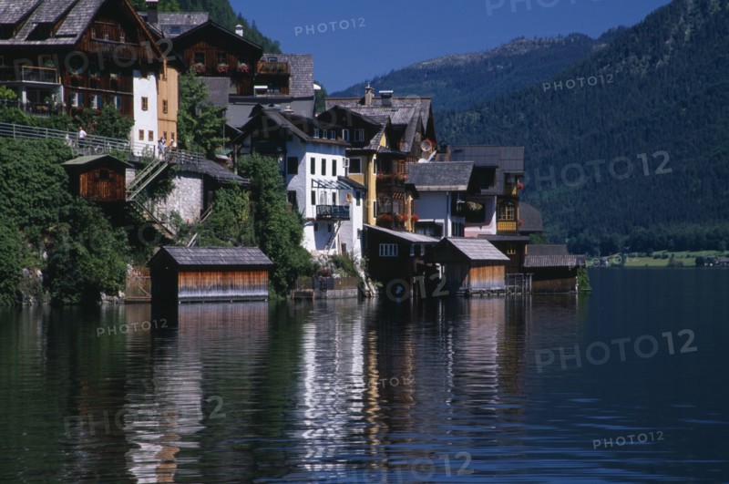 AUSTRIA, Oberosterreich, Hallstatt, Typical architecture and boat houses on shore of Hallstattersee Lake and reflected in rippled surface.