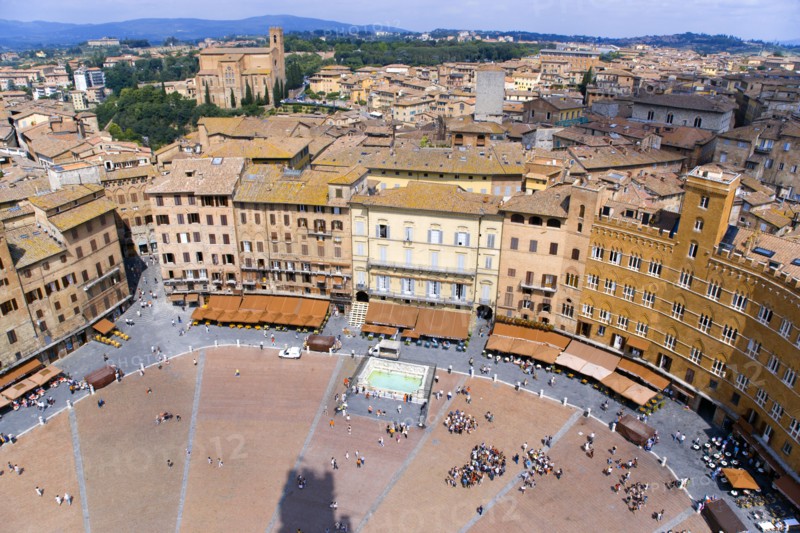 ITALY, Tuscany, Siena, View over the Piazza del Campo and the north of the city. People walk in the square past the Palazzi and restaurants that border it