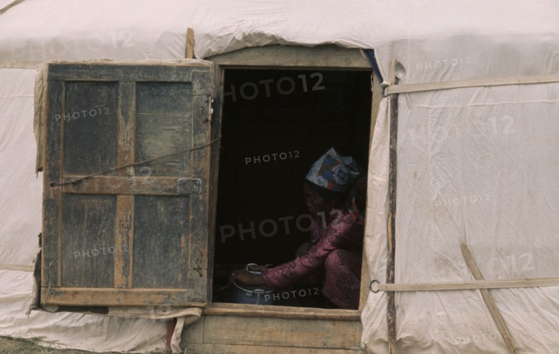 MONGOLIA, Gers Yurts, Khalkha Woman doing chores framed in open doorway of recently erected ger or yurt. East Asia Asian Female Women Girl Lady Mongol Uls Mongolian