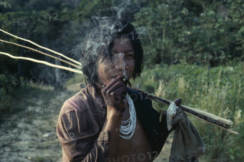 COLOMBIA, North West Amazon, Tukano Indigenous People, Barasana Indian smoking home grown tobacco and holding bar of Lux soap returns from fishing trip. Tukano sedentary Indian tribe North Western Amazonia  Western influence American Colombian Columbia Hispanic Indegent Inn Latin America Latino Pub South America Tavern Tukano One individual Solo Lone Solitary Public House