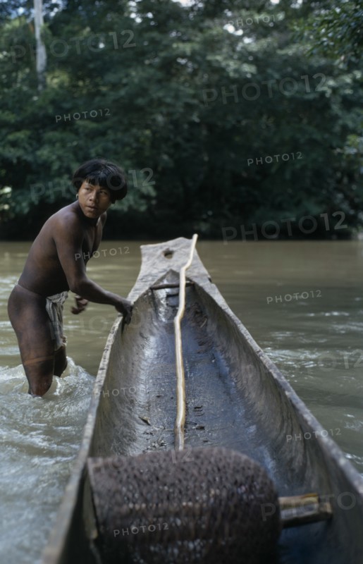 COLOMBIA, Choco, Embera Indigenous People, "Embera man, Rio Verde, standing knee deep in water beside his wooden dug out canoe. Pacific coastal region boat piragua tribe "