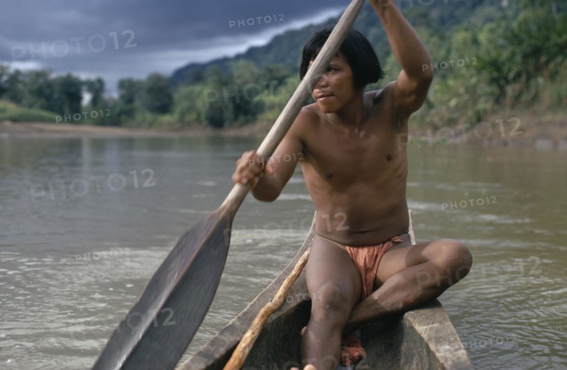 COLOMBIA, Choco, Embera Indigenous People, Embera man using single oar to steer wooden dug out canoe along rio Baudo. Pacific coastal region boat piragua tribe