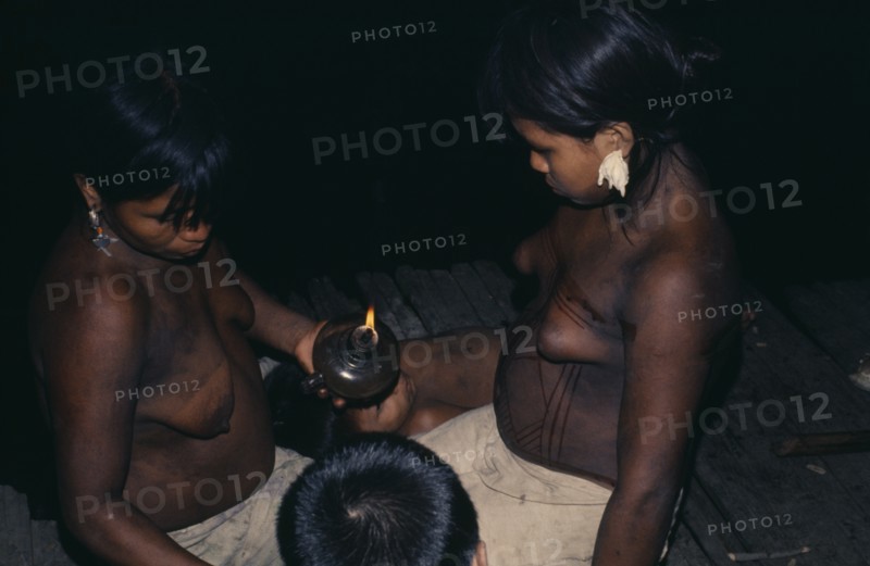 COLOMBIA, Choco, Embera Indigenous People, Young Embera daughters of the household painting their bodies with black dye extracted from the indedible Jagua fruit in preparation for curing ceremony - their mother has fever  Pacific coastal region tribe body decoration American Colombian Colombia Female Woman Girl Lady Hispanic Indegent Latin America Latino South America  Pacific coastal region tribe body decoration American Colombian Columbia Female Woman Girl Lady Hispanic Indegent Latin America Latino South America Female Women Girl Lady Immature Mum Young Unripe Unripened Green