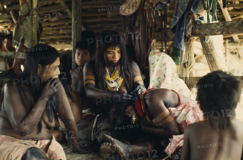 COLOMBIA, Choco, Embera Indigenous People, "Embera family group with young women painted with black dye extracted from Jagua fruit and wearing brightly coloured glass bead necklaces. Tiny glass beads  originating from Europe are coveted trade goods. Family assembled for ""canta hai"" curing ceremony   Pacific coastal region tribe body decoration American Colombian Colored Colombia Female Woman Girl Lady Hispanic Indegent Latin America Latino South America  Pacific coastal region tribe body decoration American Colombian Colored Columbia Female Woman Girl Lady Hispanic Indegent Latin America Latino South America Female Women Girl Lady Immature European Young Unripe Unripened Green "