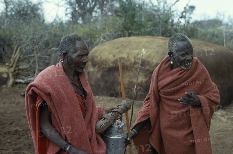 KENYA, Masai Tribe, Two old Masai men wearing traditional red clothing in their Boma.