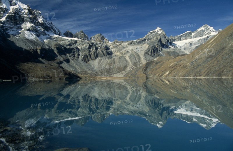 NEPAL, Everest Trek, Gokyo, View west over Dudh Pokhari Lake with snow capped mountains reflected in the water