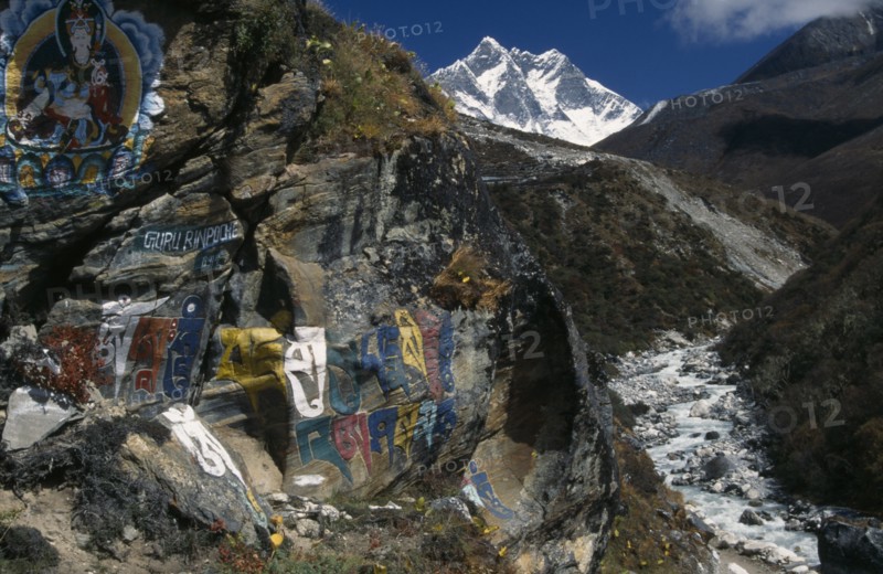 NEPAL, Everest Trek, Pangboche, Buddhist wall paintings beside the trail between Pangboche and Shomare with snow capped Lhotse mountain in the backgound