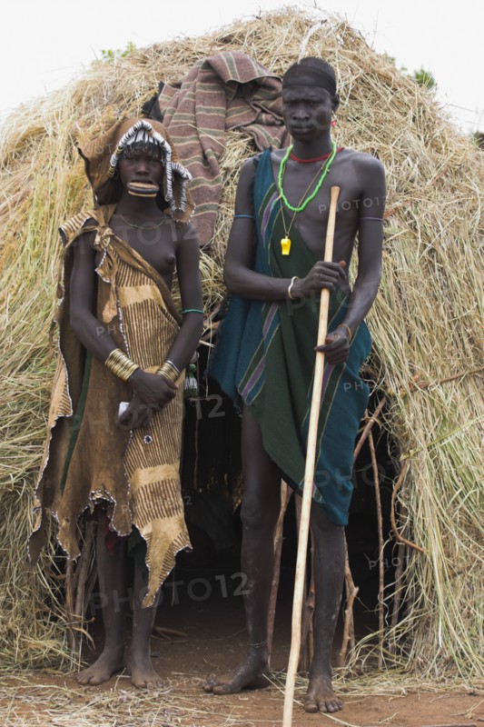 ETHIOPIA, South Omo Valley, Mursi Tribe, Couple standing outside their hut