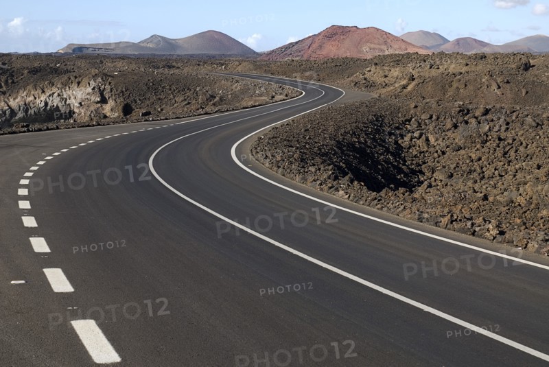 SPAIN, Canary  Islands, Lanzarote, Distant view of Timanfaya National Park and the Montanas del Fuego from scenic west coast road following bend in foreground.