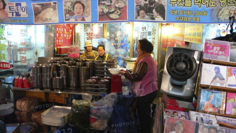 KOREA, South, Seoul, "Namdaemun market, street restaurant, women getting ready for the evening's customers behind stack of dishes"