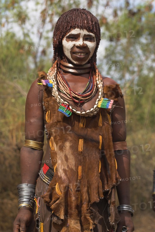 ETHIOPIA, Omo Valley, Mago National Park, "Woman with face painting, her hair greased with ocher colouring and animal fat into plaits known as Goscha and traditional goatskin dress decorated with cowrie shells "