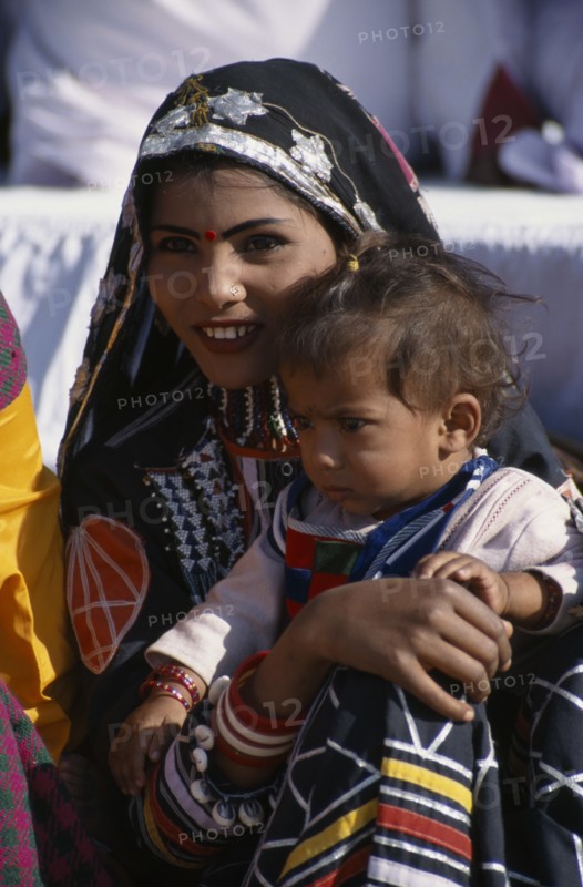 INDIA, Rajasthan, Bikaner, Kalbelia dancer woman holding her baby at the Camel Festival