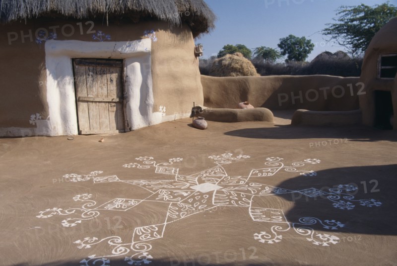 INDIA, Rajasthan, Katariasar, Village hut decorated for the Camel Festival with white painted motifs on the ground outside