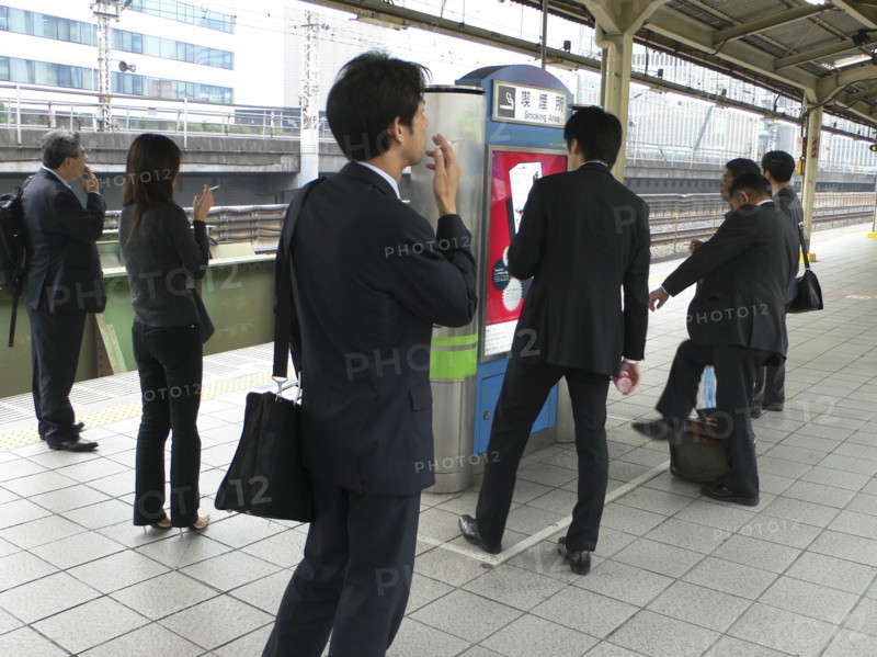 JAPAN, Honshu, Tokyo, "Yurakucho - the smokers corner on the JR train platform, men and young woman smoking"