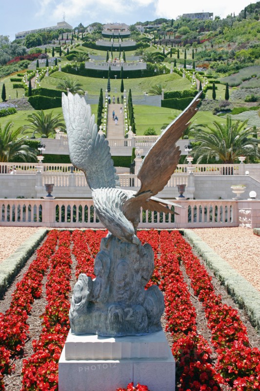 ISRAEL, Northern Coast, Haifa, Zionism Avenue.  Eagle sculpture set in flower bed of scarlet plants at the Baha'i gardens with view over tiered gardens stretching away beyond.