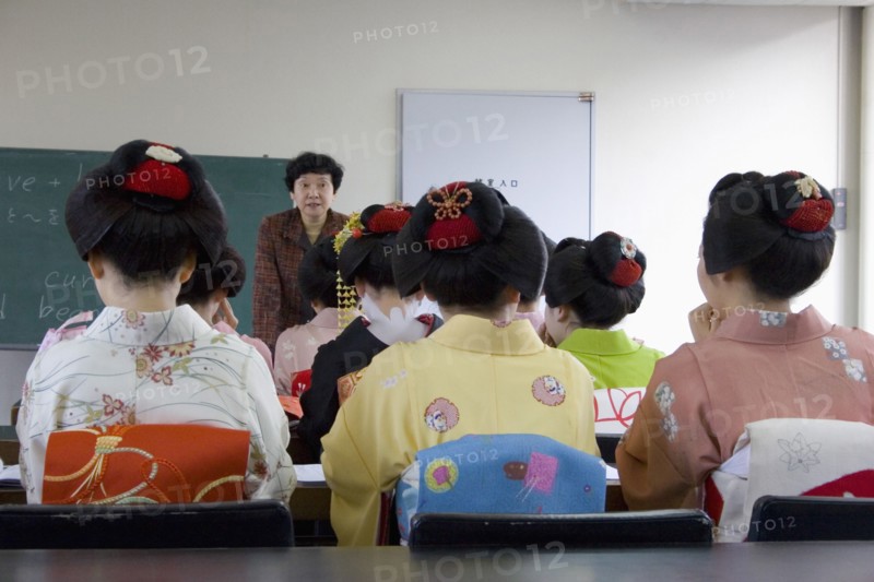 JAPAN, Honshu, Kyoto, "Gion area, the neighbourhood where Geisha live, study and perform.  Maiko apprentice Geisha attending a class at Mia Garatso school of Geisha, seated with backs to camera looking towards female teacher."