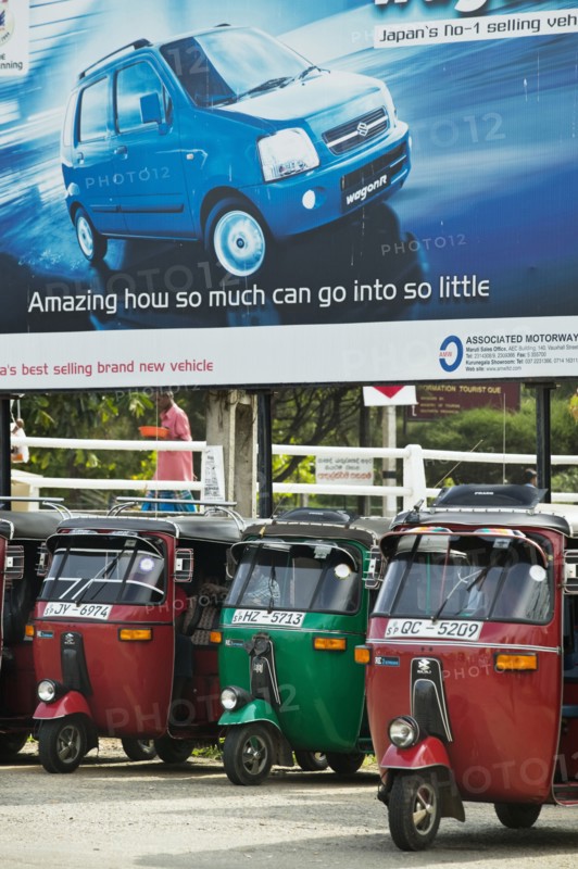 20091062 Tuk Tuks parked underneath advertising billboard Suzuki WagonR. Asia Asian Llankai Sri Lankan  Region - AsiaTransportMedia & CommunicationsDominant RedDominant Blue Jon Hicks 20091062 SRI LANKA  Transport
