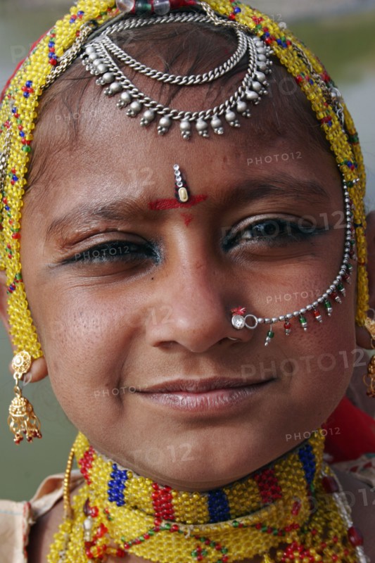 INDIA, Rajasthan, Jodhpur, Portrait of a young Indian girl at Meherangarh Fort wearing nose ring and chain and traditional bead jewelery and black kohl eyeliner.