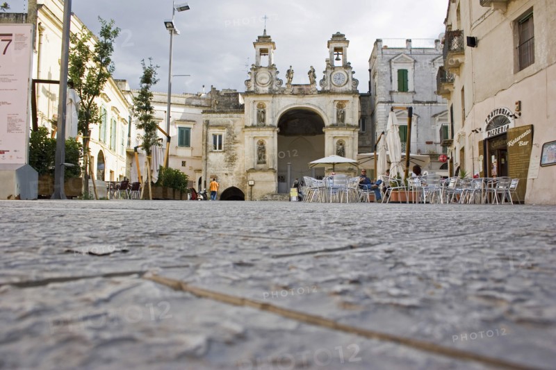 ITALY, Basilicata, Matera, Main square in ancient city of Sassi di Matera or the ‘Stones of Matera’ originating from a prehistoric cave settlement.  UNESCO World Heritage Site.  Cafe bar with outside seating overlooked by church and bell tower.