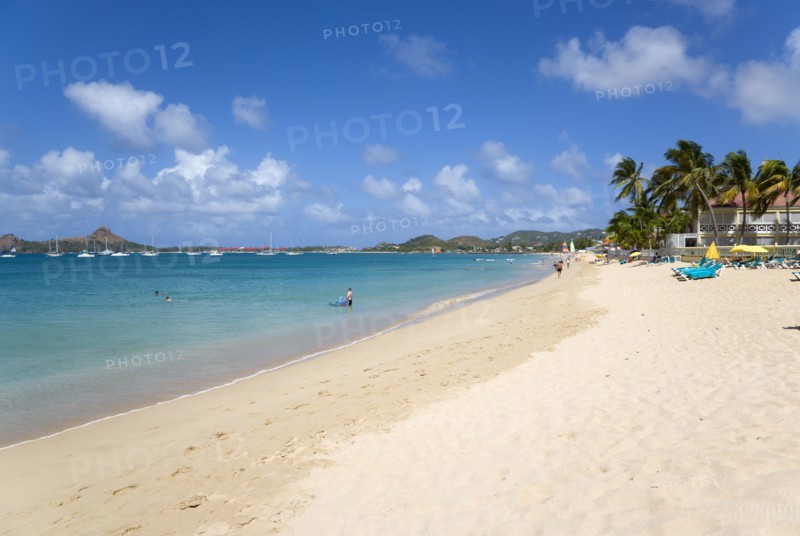 WEST INDIES, St Lucia, Gros Islet, Reduit Beach in Rodney Bay with tourists in the water and on the beach with yachts at anchor in the bay