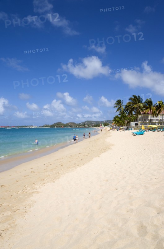 WEST INDIES, St Lucia, Gros Islet, Reduit Beach in Rodney Bay with tourists in the water and on the beach with yachts at anchor in the bay