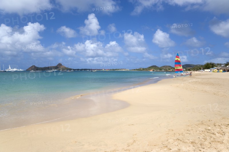 WEST INDIES, St Lucia, Gros Islet, Reduit Beach in Rodney Bay with tourists in the water and on the beach with yachts at anchor in the bay