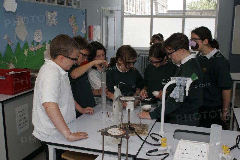CHILDREN, Education, Secondary, Food technology science pupils carrying out an experiment to measure the evaporation of a salt solution using a bunsen burner.