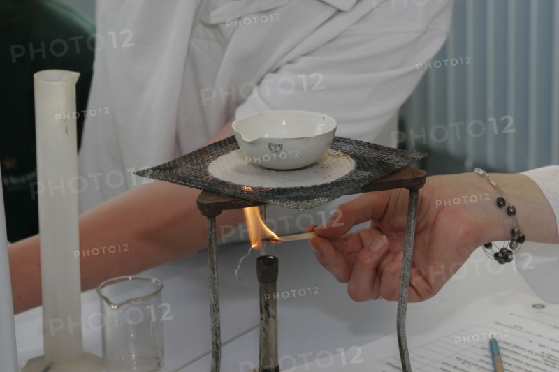 CHILDREN, Education, Secondary, Teacher lighting a bunsen burner prior to it being used for a food technology experiment measuring the evaporation of a salt solution.
