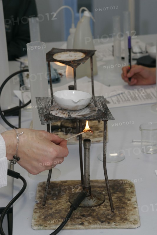 CHILDREN, Education, Secondary, Teacher lighting a bunsen burner prior to it being used for a food technology experiment measuring the evaporation of a salt solution.