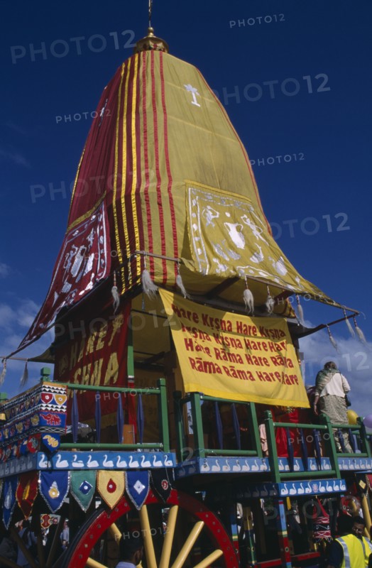 ENGLAND, East Sussex, Brighton, Hare Krishna taking part in a parade on Brighton seafront  with a colourful painted carriage