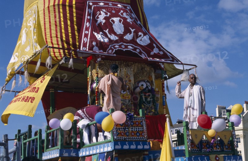 ENGLAND, East Sussex, Brighton, Hare Krishna taking part in a parade on Brighton seafront  with a colourful painted carriage